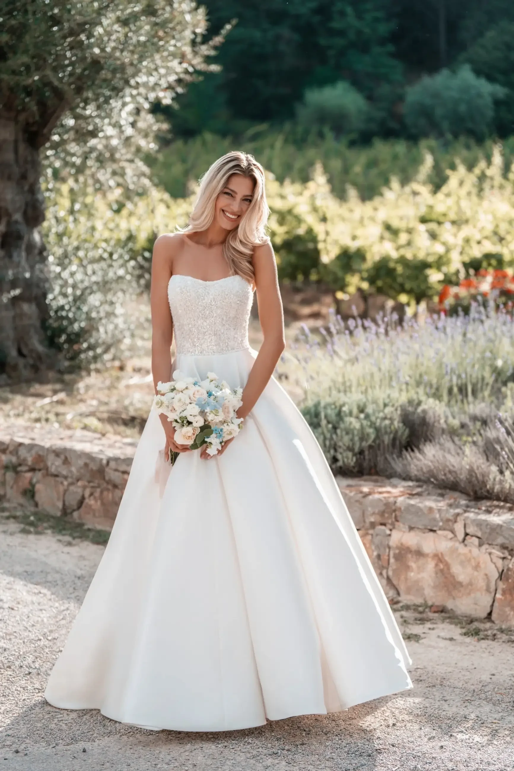 Model is wearing a strapless Mikado ballgown with an artfully draped skirt and a sparkling beaded bodice.