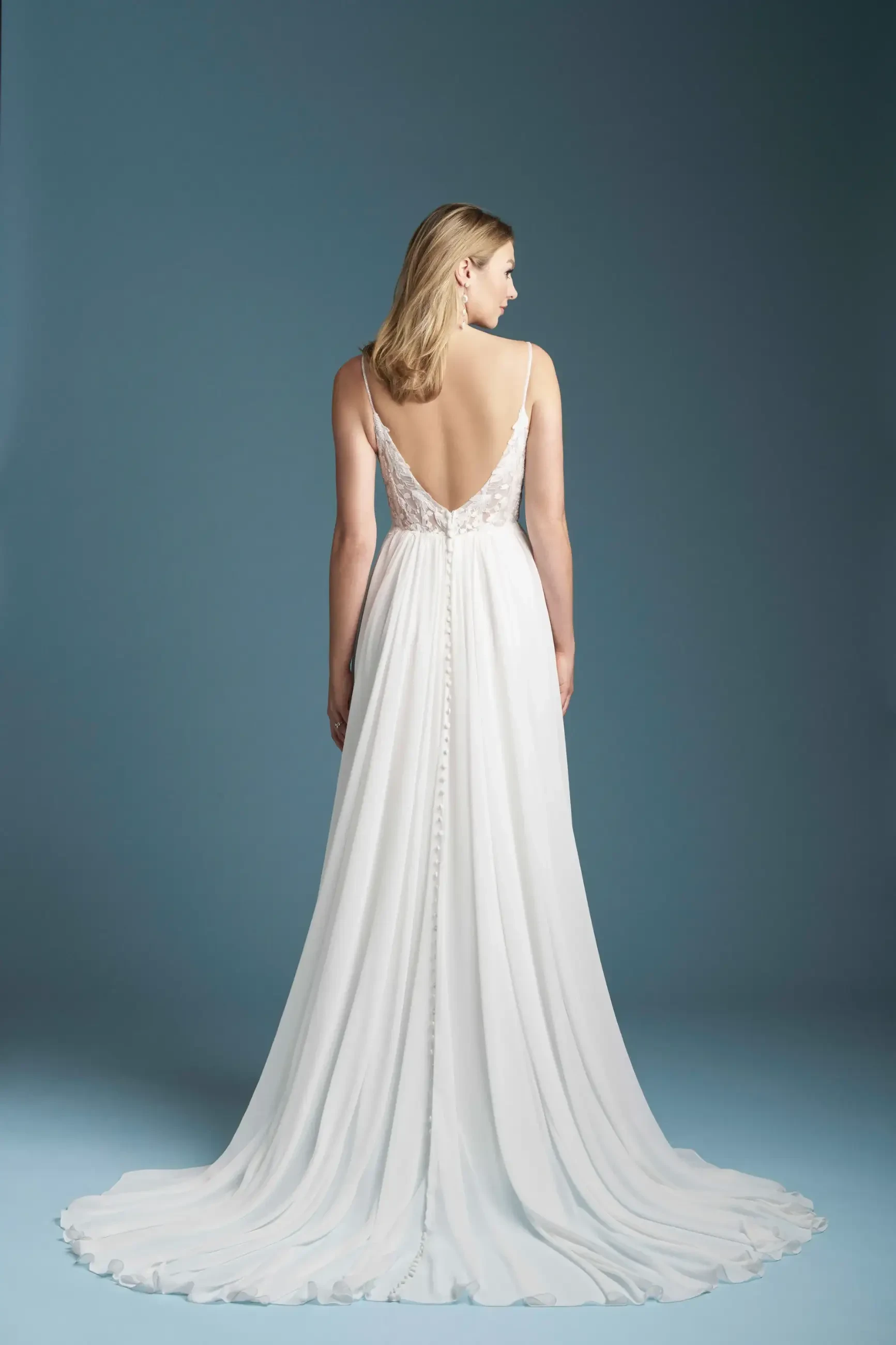 Model is wearing a romantic A-line gown with a beaded and sequin lace bodice, delicate spaghetti straps, and a light chiffon skirt that flows effortlessly.