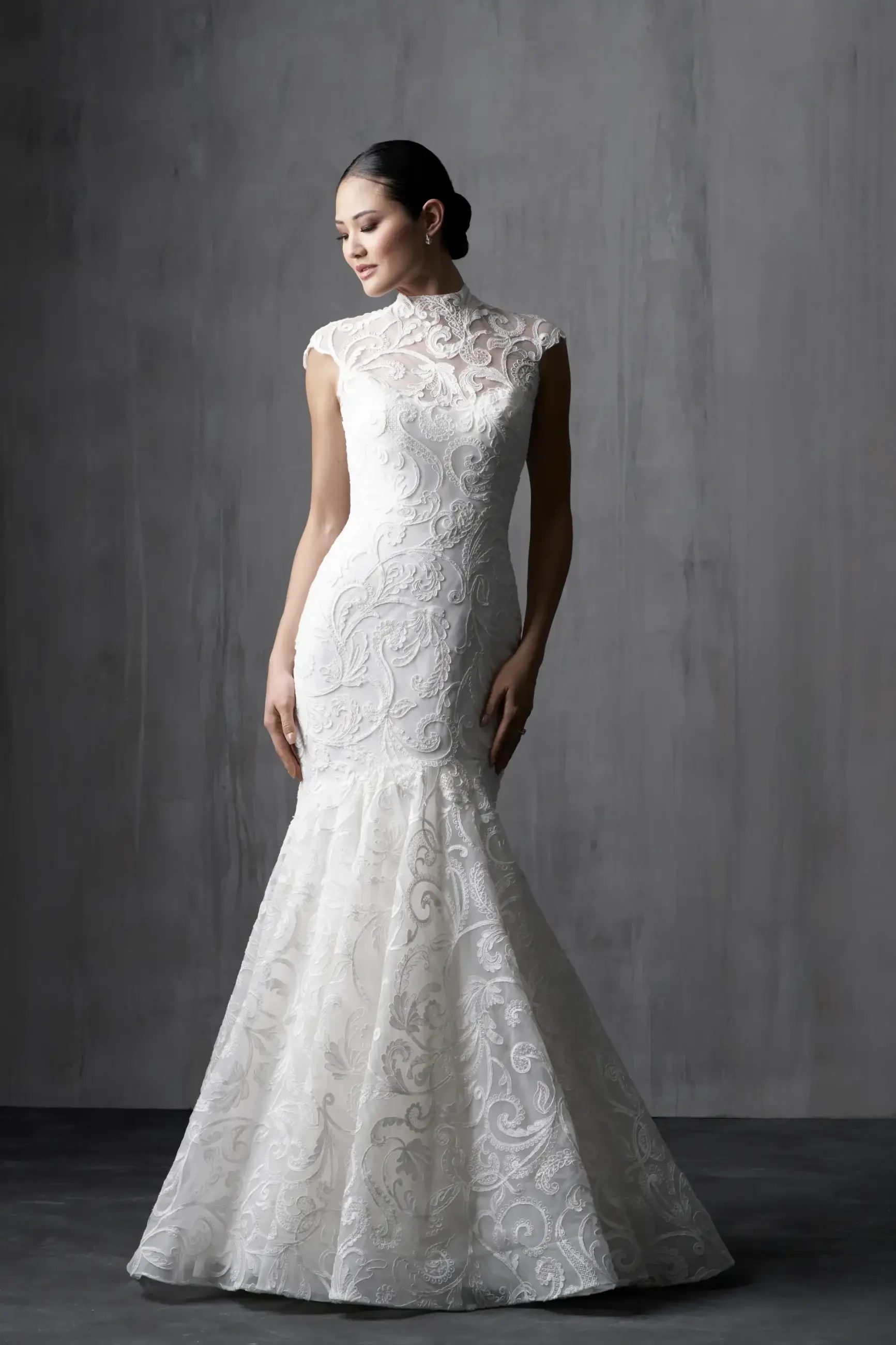 Model is wearing a sleek satin mermaid gown with a scoop neckline, sleeveless bodice, contoured silhouette, and flared skirt for a striking modern look.