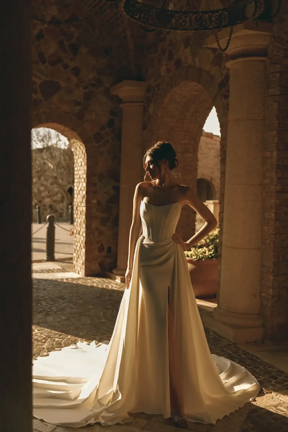model is wearing a strapless bridal gown with an overskirt
