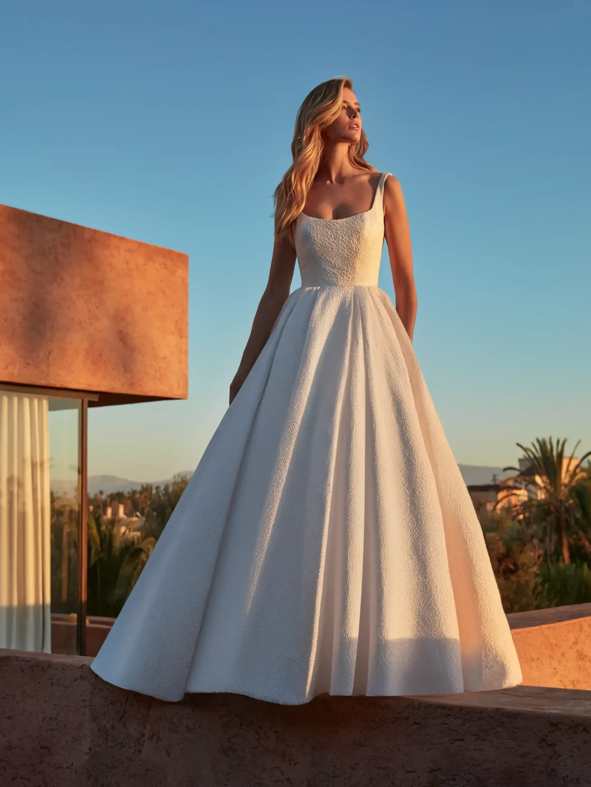 model is wearing a sleek sleeveless ball gown wedding dress